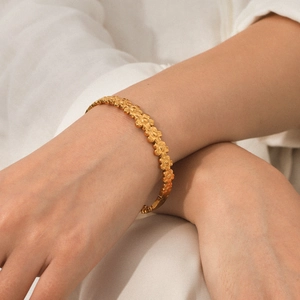 Detail of 18K gold plated stainless steel floral bracelet with daisy chain design on wrist