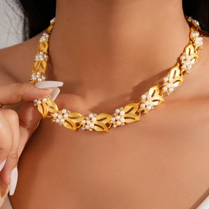 Dettaglio della collana vintage a foglia dorata con perle bianche e zirconi sul collo