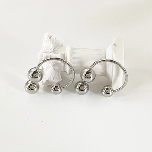Macro view of polished silver triple-bead C-shaped earrings on a white column stand