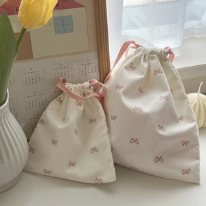 Detail of cream drawstring bags in two sizes with pink bow print in cozy home setting