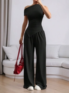 Detail of black one-shoulder top and high-waisted wide-leg trousers on model
