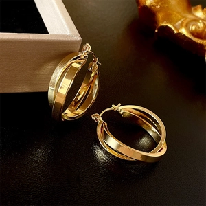 Macro shot of gold layered C-shape hoop earrings with a metallic finish on black background