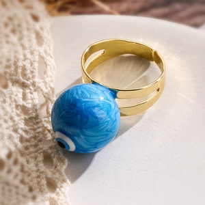 Detail of a gold adjustable evil eye ring with blue sand texture and evil eye bead