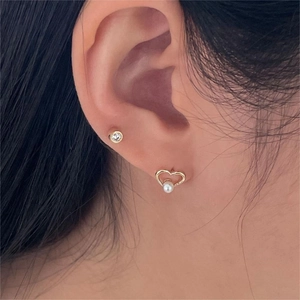 Close-up of elegant gold hollow heart earrings with pearls and round crystal studs