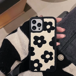 Detail shot of plush black and white floral embroidery texture on iPhone Pro case