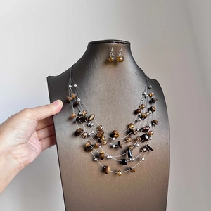 Multilayer tiger eye stone beaded necklace and earring set on a dark mannequin display