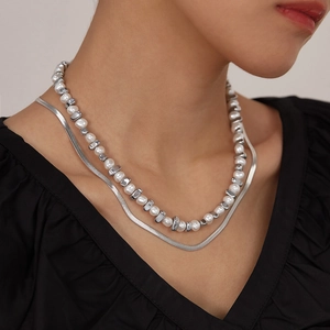 Detail of layered necklace with Baroque pearls and silver snake chain on a model