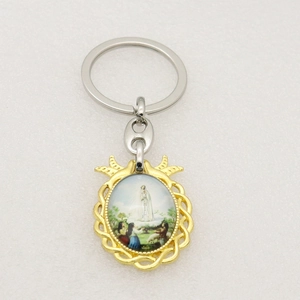 Detail of golden religious keychain showing Our Lady of Fatima and the three shepherds