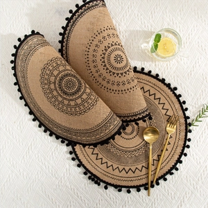 Macro shot of jute placemat with black mandala pattern and fringe tassels for table decor