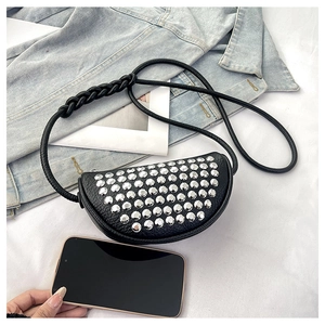Detailed view of black pebbled leather crescent bag with silver studs and braided strap