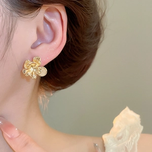 Close-up of elegant gold flower stud earring with opal stone worn by a model