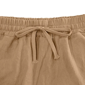 Detailed macro view of khaki linen shorts featuring elastic drawstring waist and fabric texture
