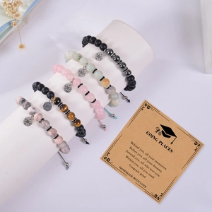 Detail view of natural stone bead bracelets with compass charms and a graduation card