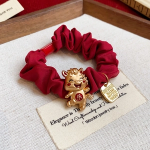 Détail du chouchou rouge orné d'un pendentif cheval doré et d'un caractère de fête chinois