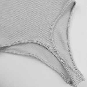 Detailed close-up of grey ribbed knit fabric and stitching on long sleeve bodysuit