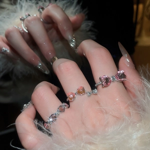 Macro detail of sparkly pink heart and bow rings with diamonds on a soft fur background