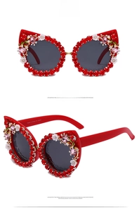 Detail view of red cat-eye sunglasses with rhinestone edges and floral carvings