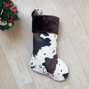 Detail of 20 inch cow print Christmas stocking with faux fur cuff on wood floor