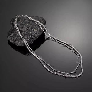 Close-up of silver double-layered titanium steel chain necklace on dark stone