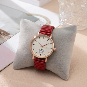 Montre élégante pour femme en or rose avec bracelet rouge sur coussin gris