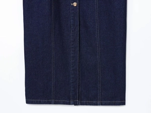 Close-up of dark blue denim dress hem with metallic buttons and yellow stitching details