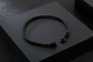 Detail of a matte black stainless steel Franco chain bracelet with a lobster clasp