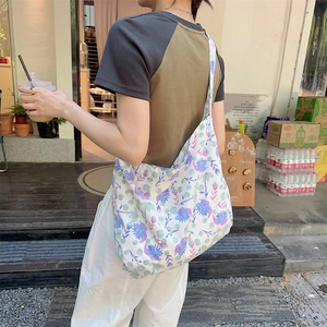 Detail of floral canvas tote bag with blue flowers showing large capacity on model