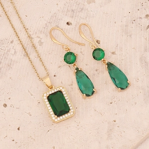 Detailed view of emerald zircon necklace and teardrop earrings set on stone