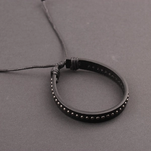 Detail of black leather punk bracelet featuring metallic rivets and adjustable cord closure