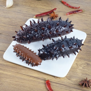 Realistic artificial sea cucumber food models displayed on a plate with spices