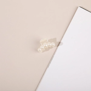 Close-up of a small cream pearl hair claw clip for hair styling and securing hair sections