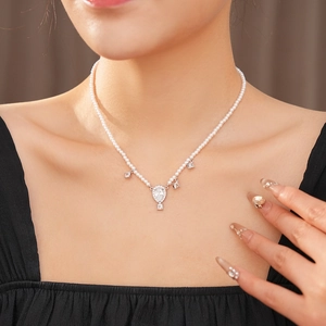 Detailed view of pearl necklace with a teardrop diamond pendant on model's neckline