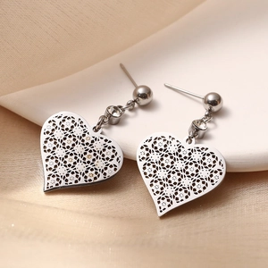 Minimalist silver hollow heart earrings in titanium steel displayed on a soft beige fabric