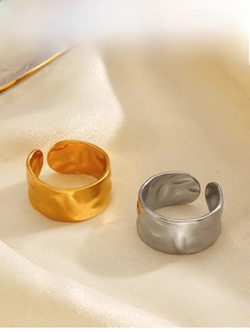 Detailed view of hammered gold and silver irregular wide rings on white silk fabric