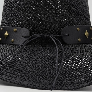 Detail of black straw cowboy hat featuring leather band with vintage metal studs