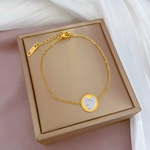 Close-up of golden stainless steel necklace with sparkling heart-shaped diamond pendant