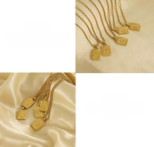 Détail de pendentifs carrés en acier titane lettres A-E avec chaîne torsadée dorée