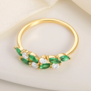 Close-up of gold ring with green marquise stones and white diamonds in leaf design