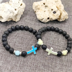 Detailansicht der leuchtenden Lavastein-Armbänder mit blau und grün strahlenden Kreuzen