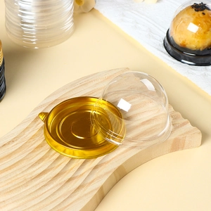 Clear plastic dome lid with gold base for mooncake packaging on a wooden tray