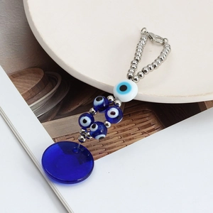 Detail of blue glass evil eye keychain with silver chain on a decorative tray
