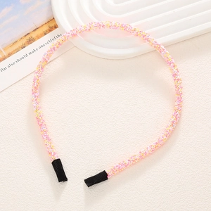 Détail de serre-têtes à paillettes roses et jaunes sur fond blanc minimaliste
