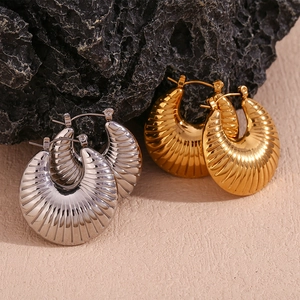 Detailed view of chunky hollow gold and silver earrings with vintage shell texture