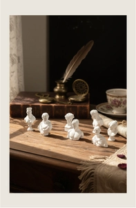 Classic mini resin bust statues on vintage wooden desk with feather pen and books