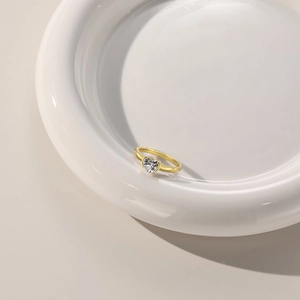 Macro shot of a heart-shaped zircon stone on a gold ring over white ceramic