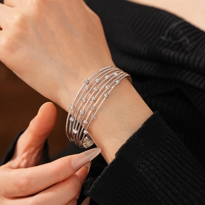 Détail d'un bracelet manchette argenté multicouche à perles sur le poignet d'un mannequin