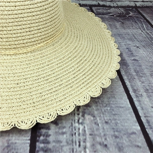 Close-up of beige woven straw hat featuring elegant scalloped edge and detailed texture