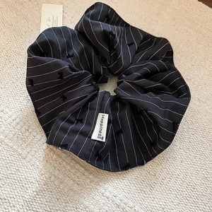 Détail d'un chouchou à rayures avec étiquette Happiness sur un tapis beige texturé