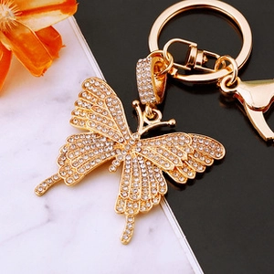 Detail of gold butterfly keychain with sparkling crystal rhinestones on marble surface