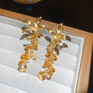 Gros plan détaillé de boucles d'oreilles fleurs dorées avec cristaux champagne sur velours